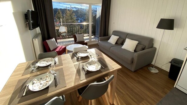 A modern living room with a dining table set for two, a grey sofa, and a large window offering a mountain view. - 150m from shops, 2nd floor, balcony, tv, ski locker, 40m², Flaine (Flaine)