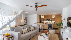 Una sala de estar moderna con un sofá gris, una mesa de centro y una escalera que sube a un nivel superior.