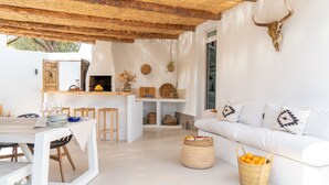 Un espacio habitable moderno y minimalista con una cocina rústica, paredes blancas y techo de madera.