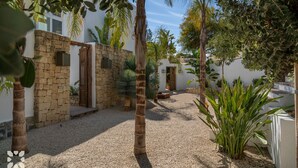 Un patio con muros de piedra, palmeras y un sendero de grava.