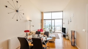 Ein modernes Wohnzimmer mit Essbereich, großen Fenstern und Meerblick.