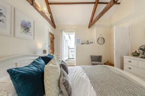 Une chambre à coucher avec un lit, une chaise, une commode et une fenêtre.