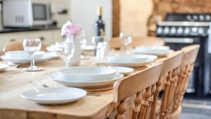 A dining table set with plates, glasses, and cutlery, with a microwave and oven in the background. - 3 Bed in Meshaw (oc-d29056) (Meshaw)