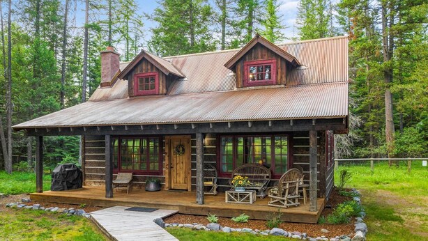 Eine rustikale Holzhütte mit Veranda, Holzterrasse und Schornstein.