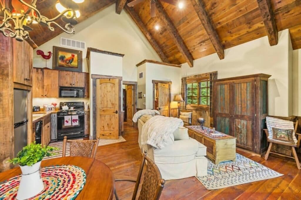 A rustic interior with wooden beams, a kitchen with modern appliances, a cozy seating area, and a large wooden cabinet.