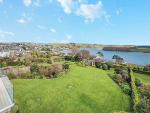 A well-maintained lawn with a glass conservatory, a view of a coastal town, and a body of water.