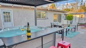 Un espace extérieur avec un jacuzzi, un bar, des sièges et un petit jardin.