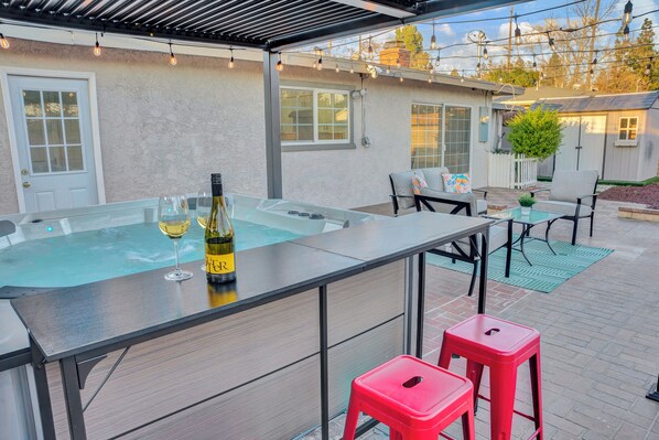 Un espace extérieur avec un jacuzzi, un bar, des sièges et un petit jardin.