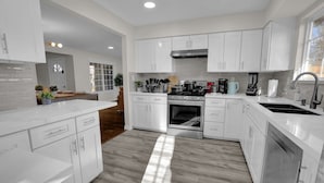 Une cuisine moderne avec des meubles blancs, un îlot central et un four encastré.