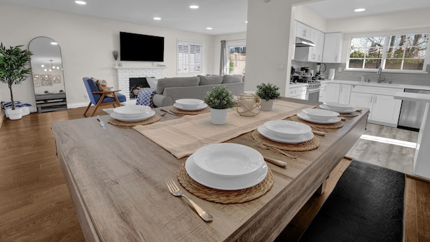 Une cuisine moderne avec des meubles blancs, un grand îlot central doté d’un plan de travail en bois et un coin repas aménagé pour six personnes.