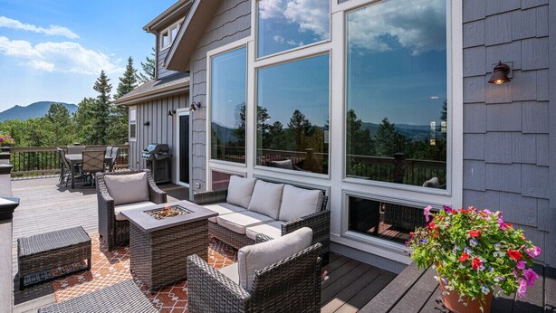 Une terrasse dotée de meubles en osier, d’un barbecue et d’une plante en pot.