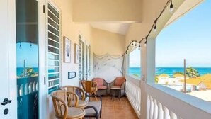 A balcony with wicker furniture, a view of the sea, and a tiled floor. - Golden Dream Villas & Studio A/B Poll View (Isabela)