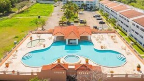 A hotel with a central swimming pool, multiple buildings, and a well-maintained lawn. - Golden Dream Villas & Studio A/B Poll View (Isabela)