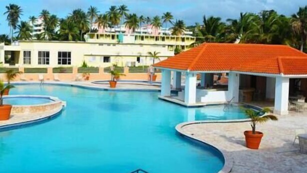 A swimming pool with a covered area and palm trees in the background. - Golden Dream Villas & Studio A/B Poll View (Isabela)