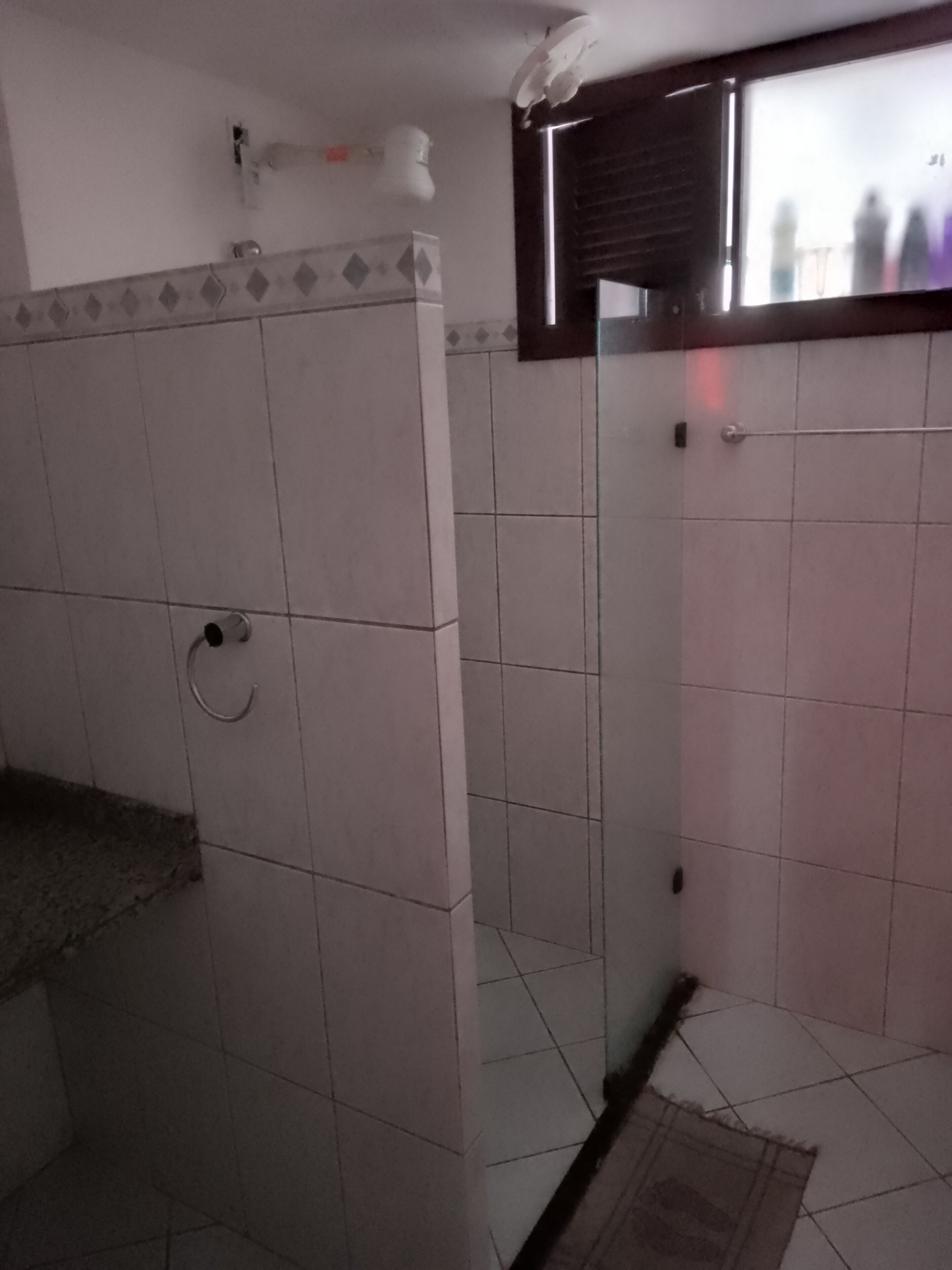 Un baño con paredes de azulejos blancos, un inodoro, un lavabo y una zona de ducha.