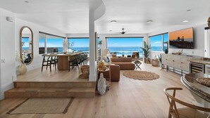 Un amplio salón con vistas al océano, un comedor con una mesa grande y una cocina con electrodomésticos modernos.