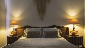 A neatly made bed with a headboard, two bedside tables with lamps, and a macrame wall hanging. - Casona El Resguardo (San Esteban)