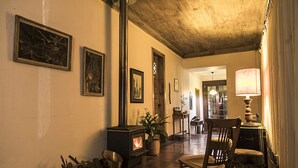 A hallway with a fireplace, wooden chairs, and framed artwork on the walls. - Casona El Resguardo (San Esteban)