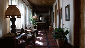 A hallway with a wooden ceiling, patterned chairs, a lamp, and potted plants. - Casona El Resguardo (San Esteban)