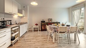 A modern kitchen with white cabinets, a dining area with a table and chairs, and a wooden floor.