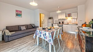 A modern living room with a sofa, dining table, and kitchen area.
