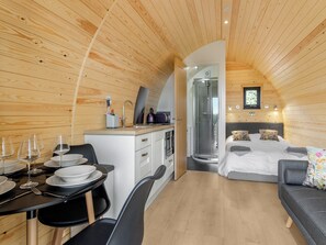Um espaço interior compacto, em madeira, com área de jantar, cozinha compacta e chuveiro.
