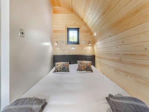 A bedroom with a bed, two pillows, a window, and a light fixture.