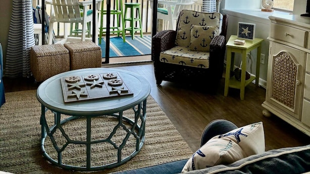 Een gezellige woonkamer met uitzicht op een veld, een ronde salontafel, een bank en een fauteuil.