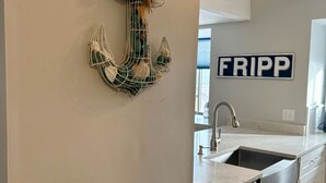 Een keuken met een wit aanrecht, roestvrijstalen apparatuur en een decoratief anker dat hangt.