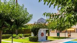 A swimming pool area with a lifebuoy, a bench, and a view of a mountain. - Santa Barbara Serena Apartment Jávea (Javea / Xàbia)