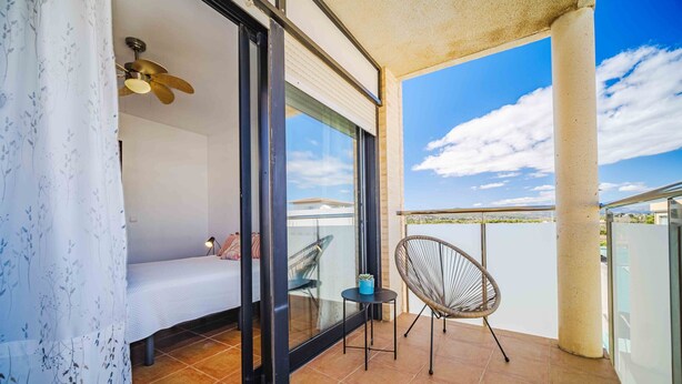 A balcony with a bed, a chair, and a ceiling fan. - Santa Barbara Serena Apartment Jávea (Javea / Xàbia)