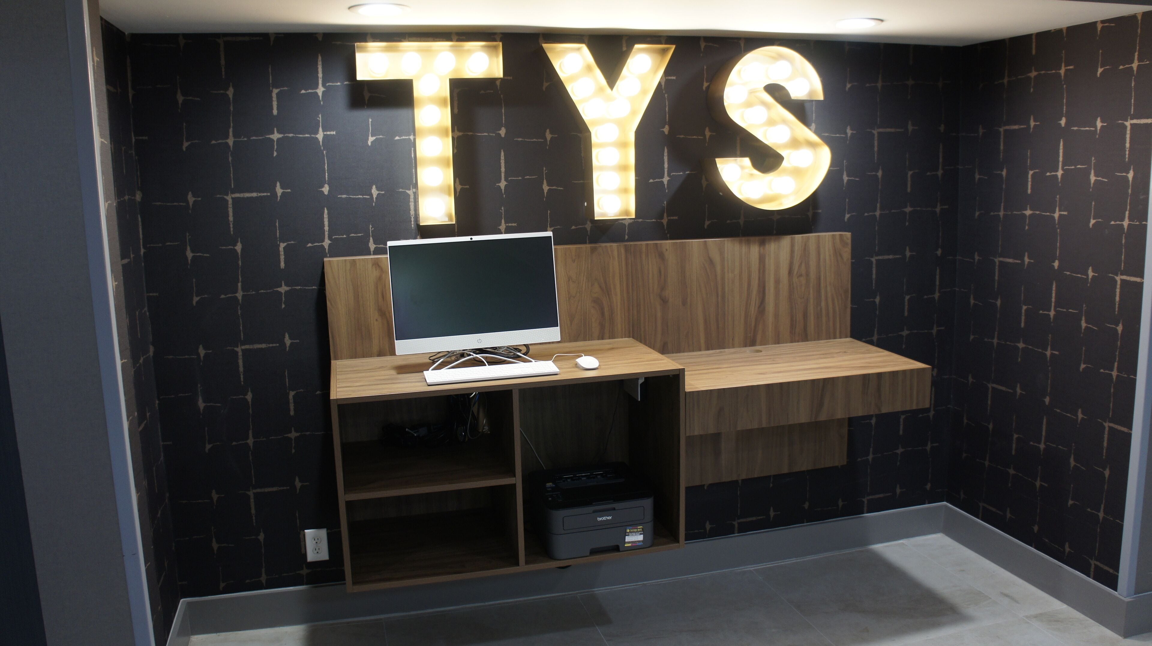 A computer desk with a monitor, keyboard, and mouse, and a printer below it.