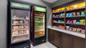 Dois dispensadores de bebidas com a etiqueta 'Bright Side Market', com prateleiras repletas de lanches e bebidas.