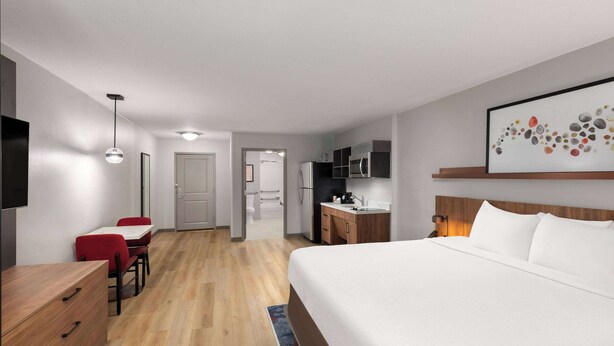 Quarto de hotel com uma cama grande, escrivaninha, cadeira, televisão e micro-ondas.