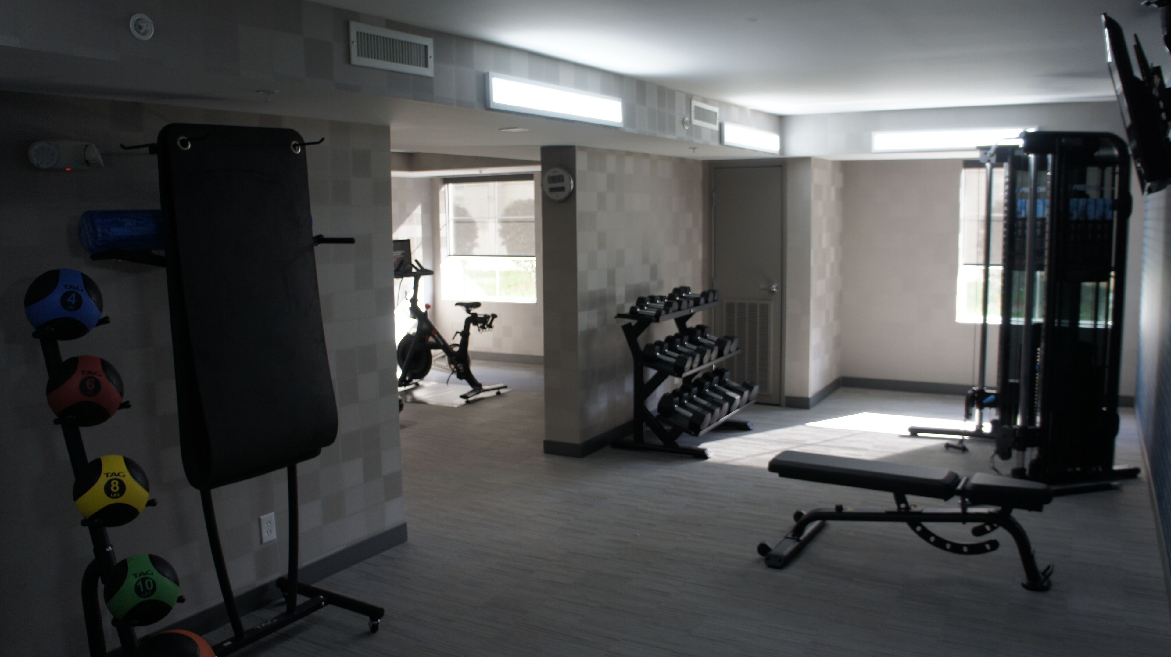 A gym with exercise equipment, a bench, and dumbbells.