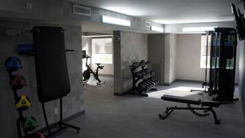 A gym with exercise equipment, a bench, and dumbbells.