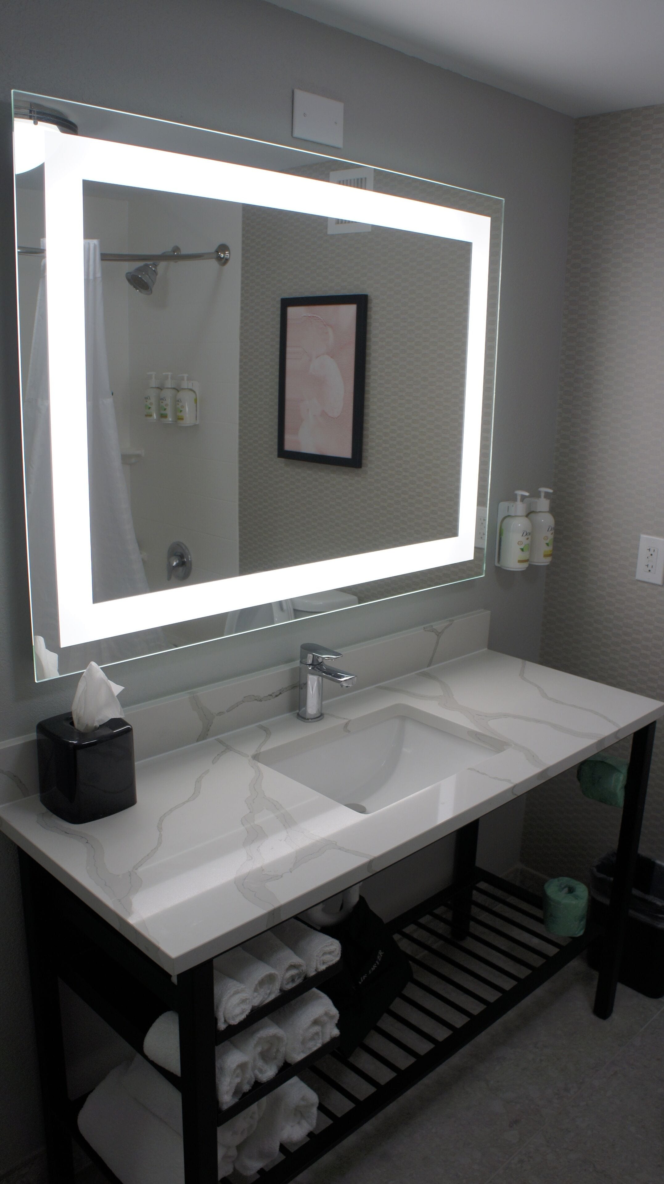 Une salle de bain avec un grand miroir, deux lavabos, un porte-serviettes et un rideau de douche.