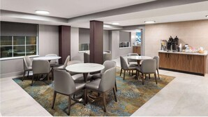 Quarto de hotel moderno com área de refeições, bancada de cozinha e uma janela grande.