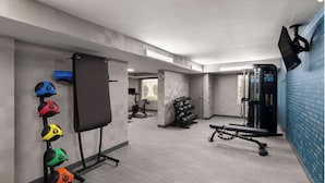 Uma academia moderna com equipamentos de musculação, um banco e uma TV fixada na parede.