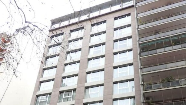 Um edifício de vários andares com design moderno, apresentando uma grande entrada de vidro e uma loja visível chamada 