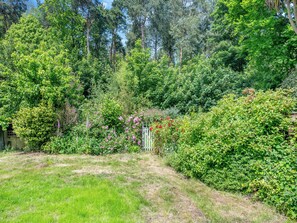 A lush garden with a variety of trees and shrubs, a wooden fence, and a grassy area. - 2 bedroom accommodation in Cromer (Cromer)