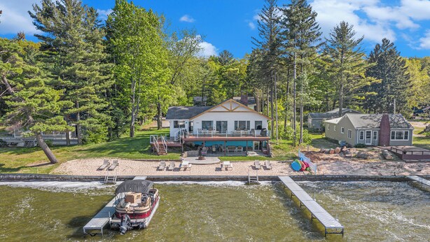 Uma casa à beira do lago com um píer, um barco e um cais.