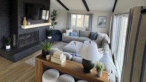 Uma sala de estar moderna com lareira, um conjunto de sofá, uma mesa de centro e uma TV na parede.