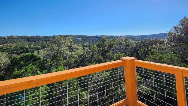 A balcony with a metal railing overlooking a forested landscape. - Brand new w/ gorgeous hill views- Ready to relax (Helotes)
