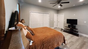 A bedroom with a bed, ceiling fan, TV, and storage cabinets. - Brand new w/ gorgeous hill views- Ready to relax (Helotes)
