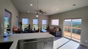 A spacious kitchen with a large island, a dining area with a table and chairs, a sofa, and a balcony with a view. - Brand new w/ gorgeous hill views- Ready to relax (Helotes)
