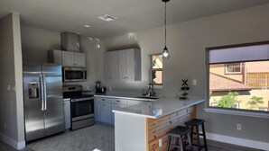 A modern kitchen with stainless steel appliances, a wooden island, and a large window. - Brand new w/ gorgeous hill views- Ready to relax (Helotes)