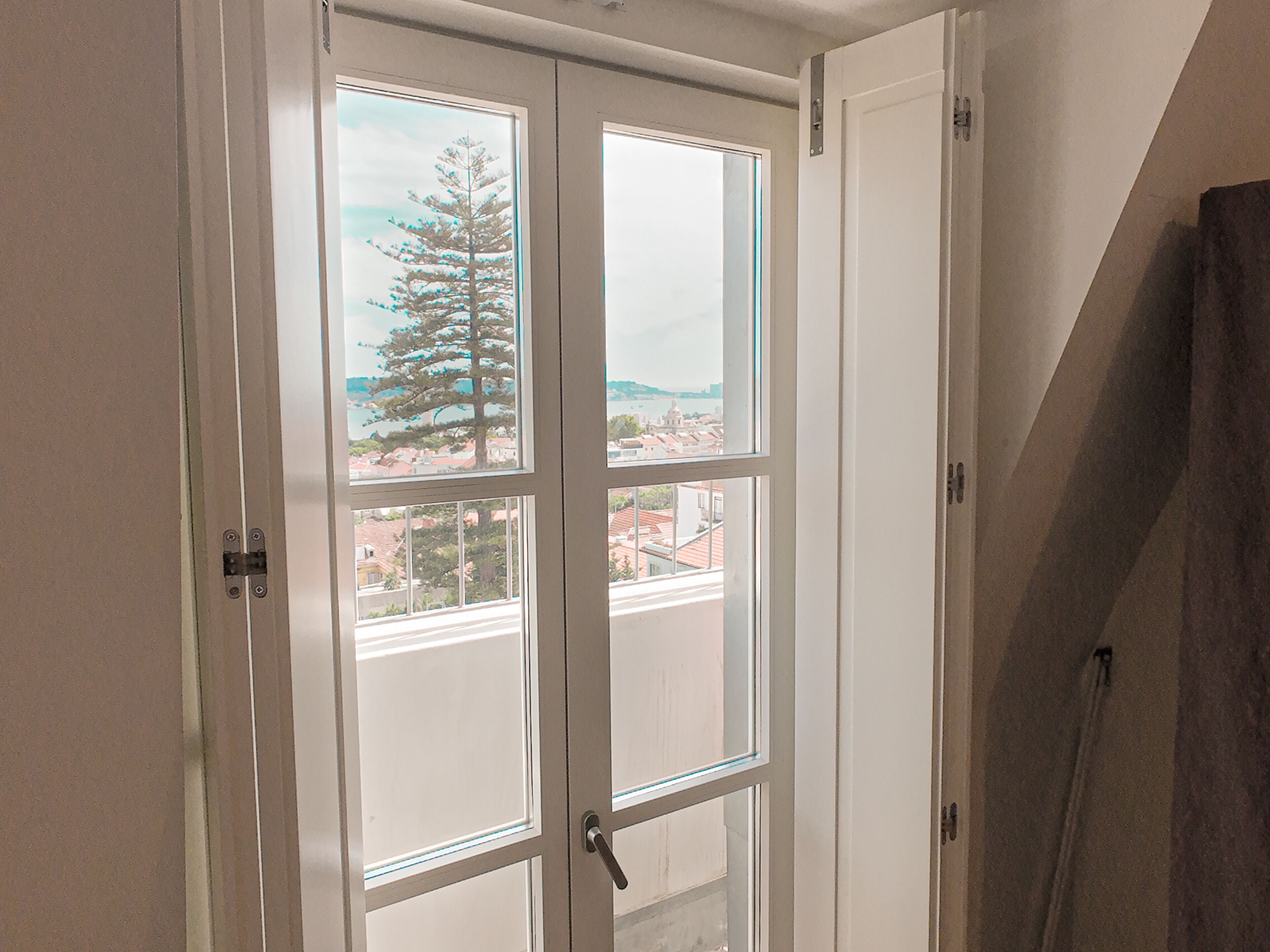 A room with a large window, a door, and a wooden structure leaning against the wall.