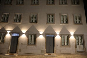 A multi-story building with uniformly lit windows and doors, arranged in a symmetrical pattern. - Ajuda Palace Inn Lisbon (Lisbon)