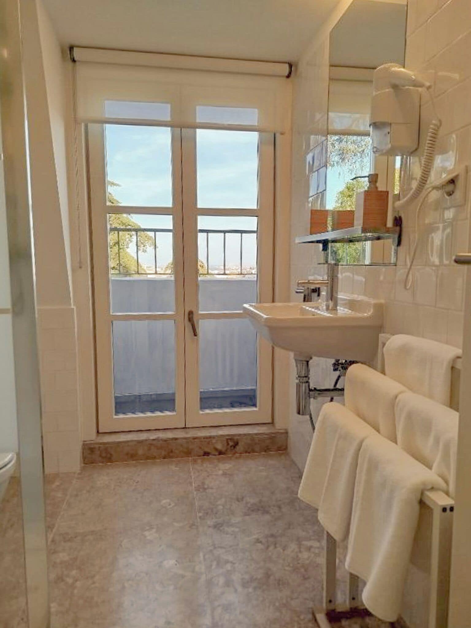 A bathroom with a sink, towel rack, and a hairdryer mounted on the wall.